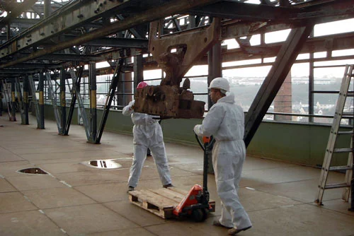 Arbeiter in Schutzanzügen bei Industriedemontage
